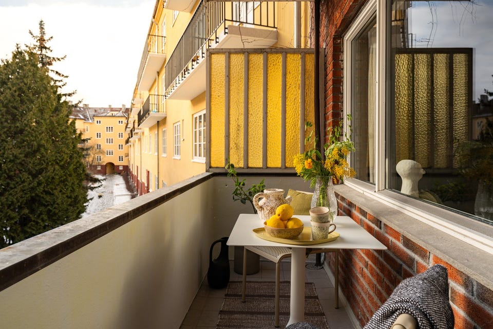 Balkongen er overbygget, har flislagt gulv og plass til hyggelig sittegruppe.