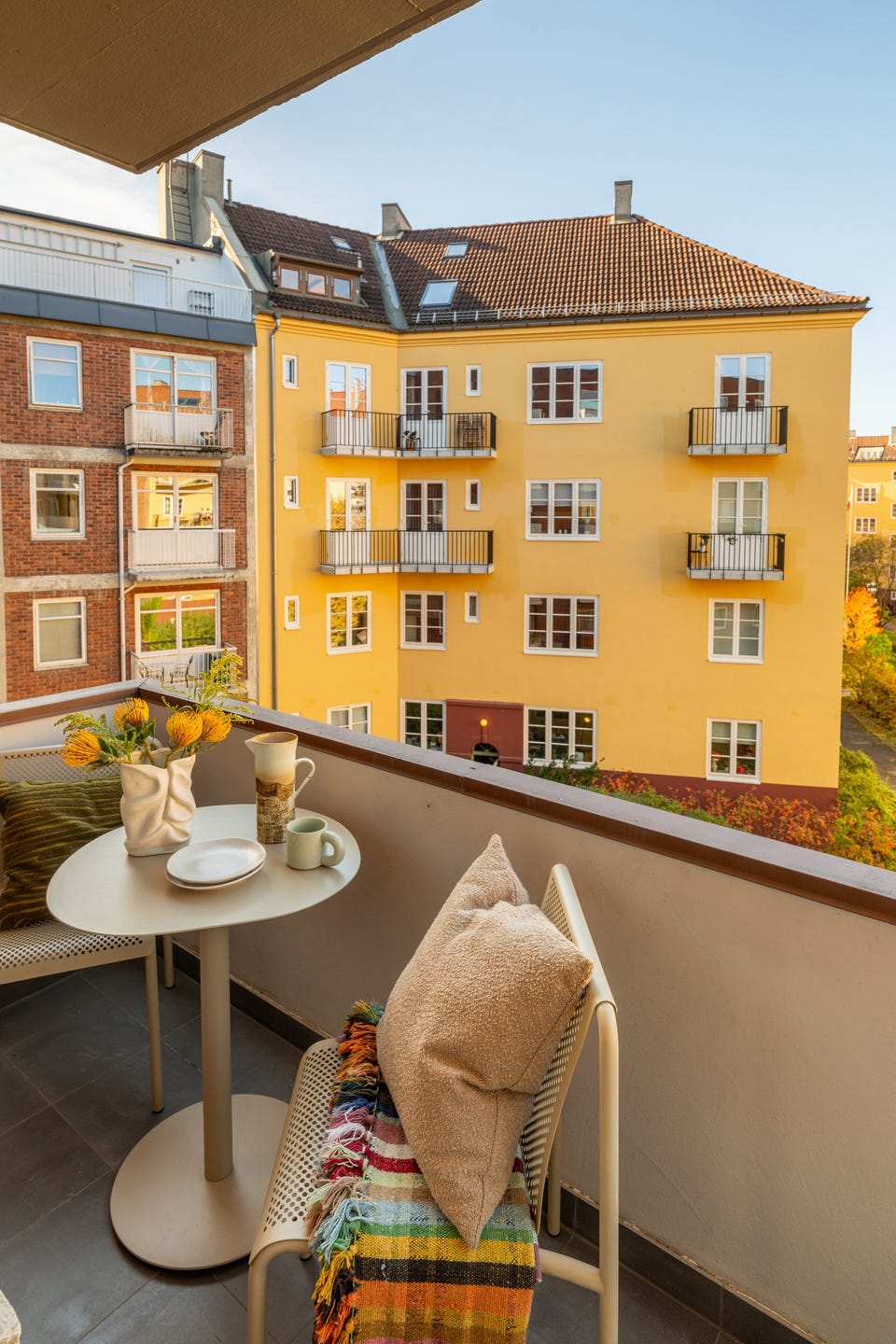 Balkongen er overbygget, har flislagt gulv og plass til hyggelig sittegruppe.