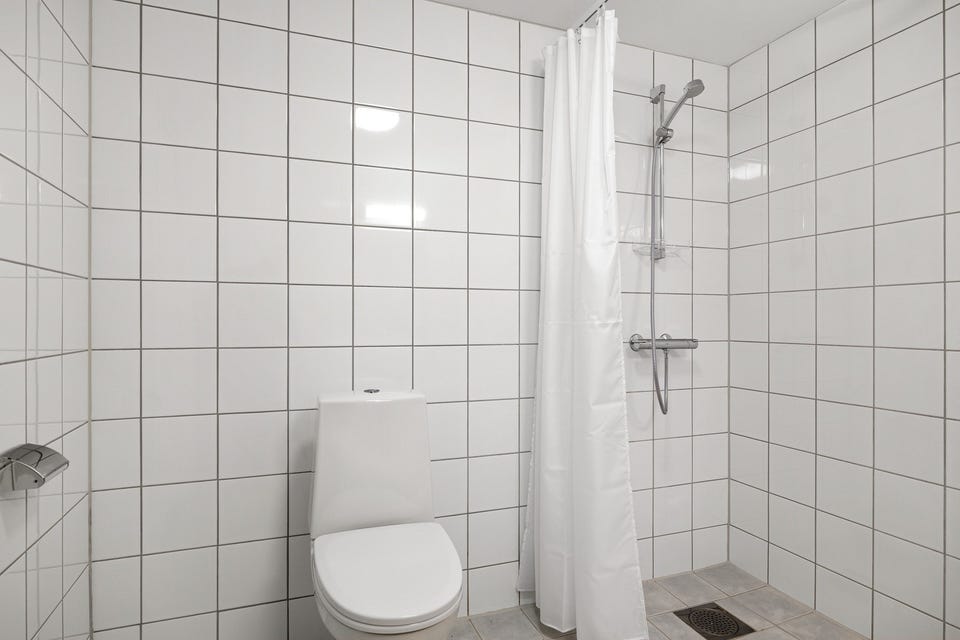 Romslig bad med fliser på vegger og gulv, samt gulvvarme.