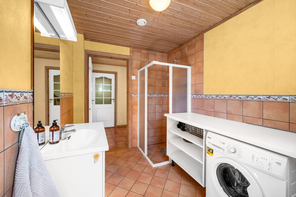 Badet i 1. etasje er fra byggeår med flislagt gulv med gulvvarme, samt flislagte vegger.
