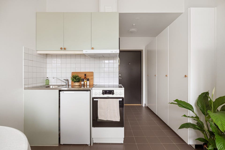 Kjøkkeninnredningen har glatte fronter, samt en benkeplate av rustfritt stål. Det er lagt fliser på veggen mellom benkeplaten og overskapene som sørger for en enklere rengjøring.