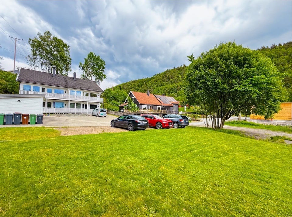 Eiendommen sett utenfra med store gressplener og gode parkeringsmuligheter.