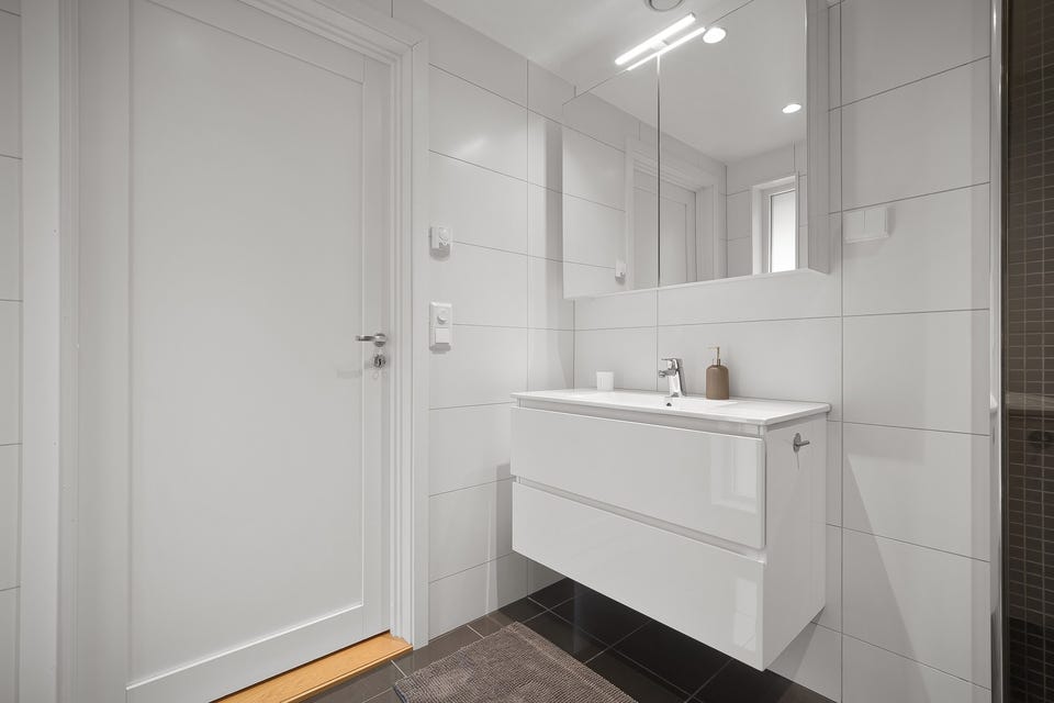 Baderom 1 har adkomst fra entréen, og er et lyst og moderne baderom fra byggeåret 2017. Baderommet har fliser på gulv og vegger, vannbåren gulvvarme, downlights i himlingen og avtrekk via balansert ventilasjon.