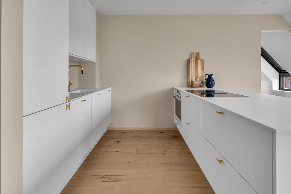 The kitchen is modern with white fronts and gold details.
