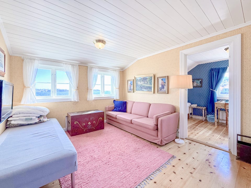 Fleksibelt oppholdsrom med sofa, seng og sjøutsikt fra flere vinduer