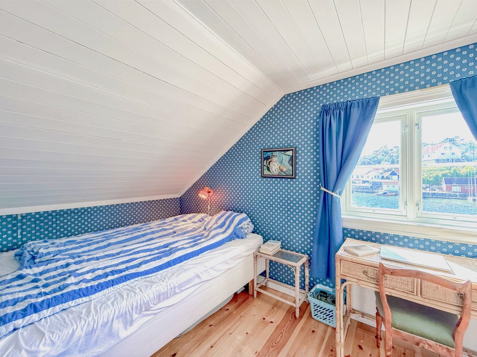 Soverom med dobbeltseng, skriveplass og utsikt mot sjøen