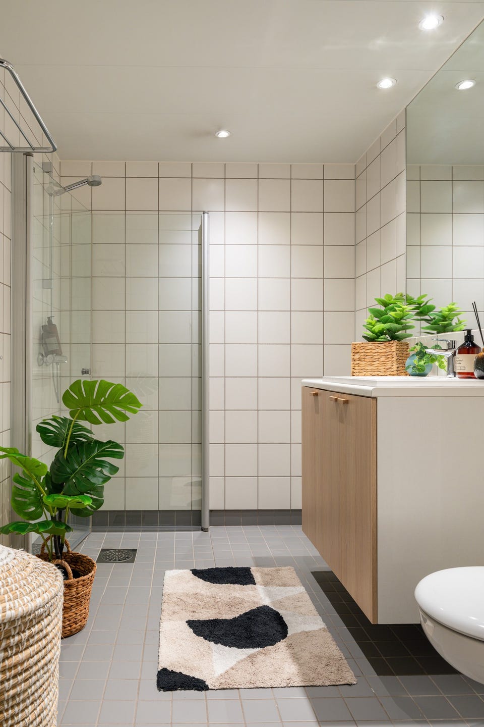 Baderommet har grå fliser på gulv, elektrisk gulvvarme, hvite fliser på veggene, downlights i himlingen og mekanisk avtrekk. I hjørnet er det plass og opplegg for vaskemaskin.