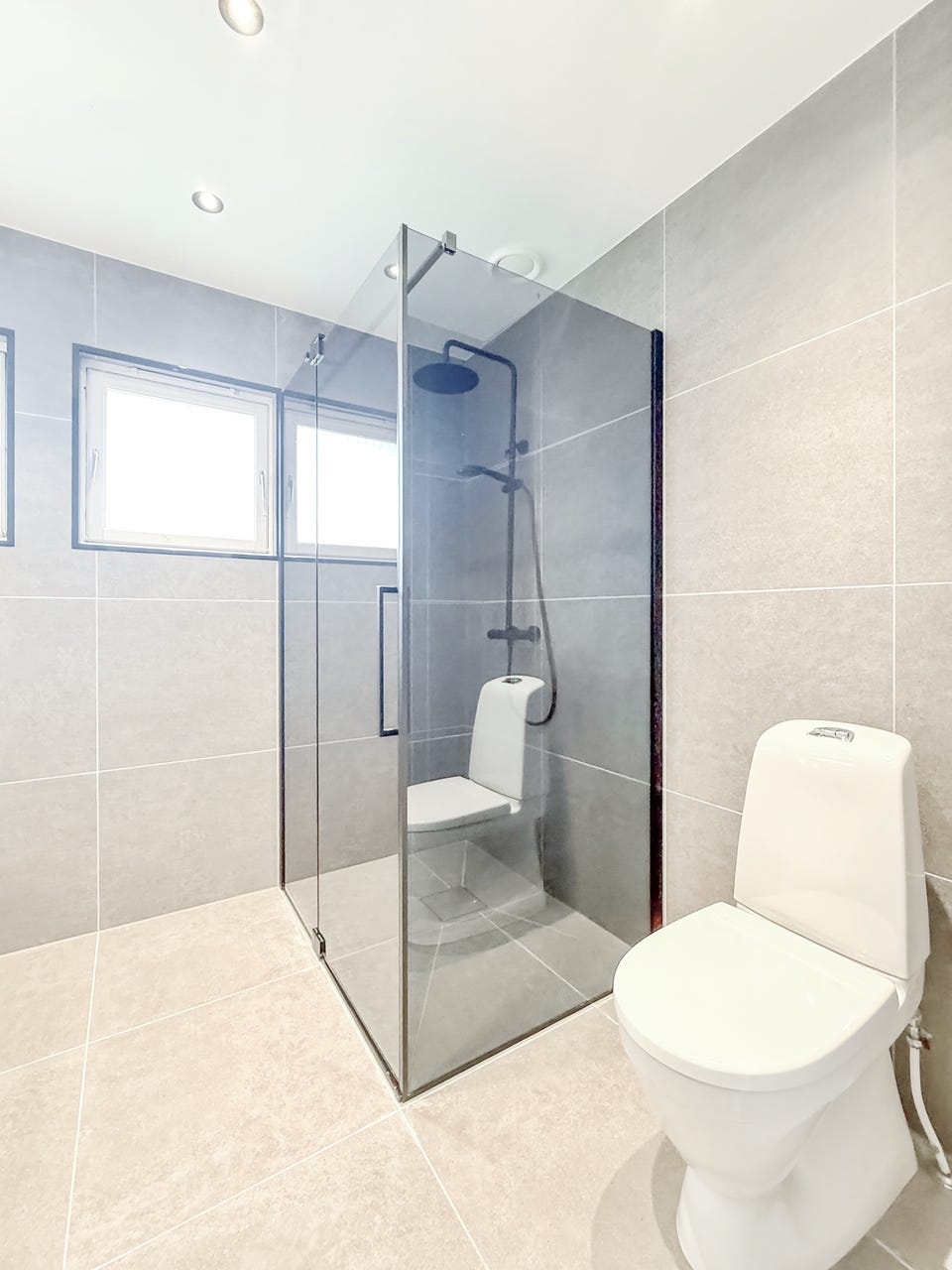 Badet har toalett og dusjhjørne med glassvegger