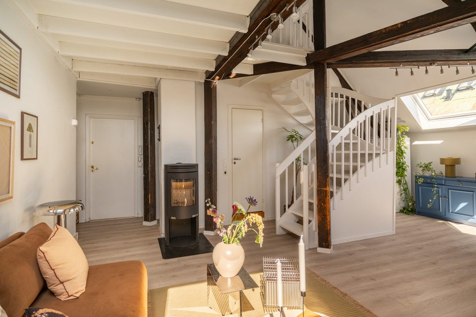 De synlige originale takbjelkene gir den lune og koselige atmosfæren som hører med i en loftsleilighet.