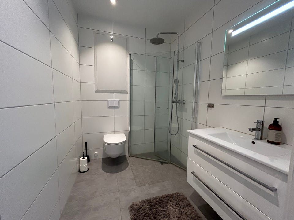Lovely bathroom with washbasin with drawers, wall-hung toilet and shower with folding doors.