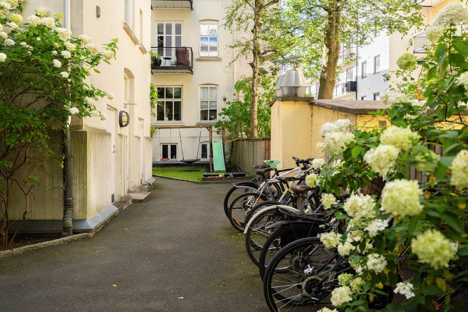 Tomten og fellesarealer er pent opparbeidet med gressplen, kantstein, beplantet, hagemøbler og sykkelparkering.