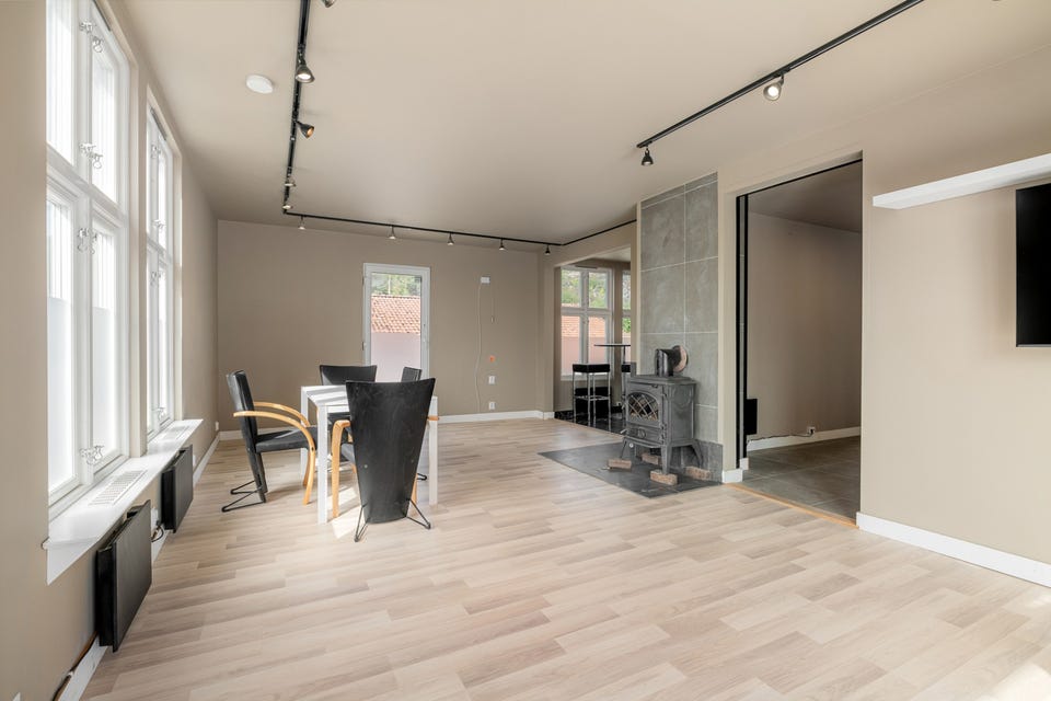 Stuen har god plass til både sofagruppe og spisebord, og de store vindusflatene bidrar til et lyst og trivelig innemiljø.