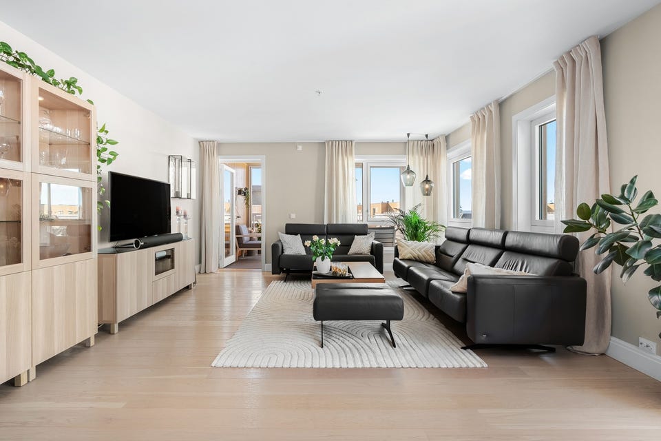 Overflatene i stuen fremstår som moderne med tidsriktige fargevalg og en-stavs parkett på gulv.
