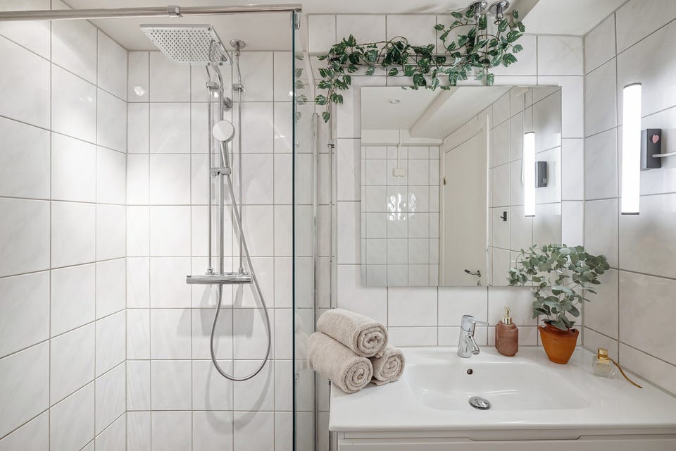 Rommet er innredet med servant med tilhørende servantskap, dusjhjørne med innfellbare glassdører og opplegg for vaskemaskin.