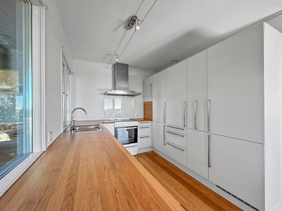 Lyst og funksjonelt kjøkken med ventilator, komfyr og moderne løsninger.