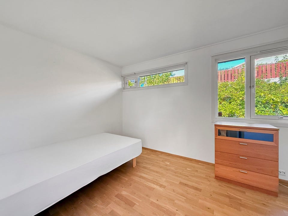 Lyst soverom med parkettgulv og vindu som gir godt dagslys. Soverommet har stor skyvedørsgarderobe.