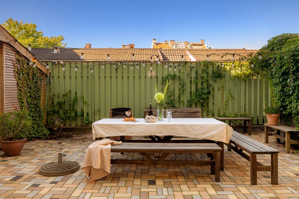 Felles tomt opparbeidet med blant annet asfalterte veier, belegningsstein, terrasse på terreng, blomsterkasser, sittegrupper, og andre forskjellige beplantninger.