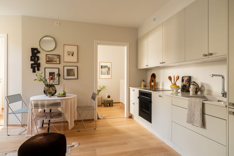 HTH-kjøkken med slette beige fronter og steinbenkeplate. Spisebordet står naturlig plassert ved siden av kjøkkenet.