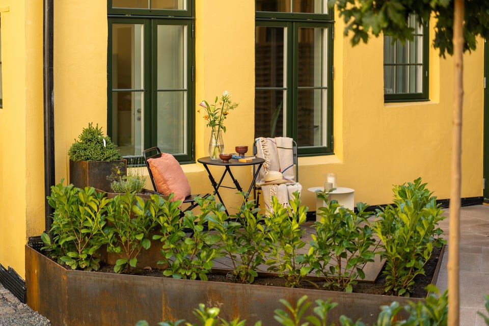 Beplantningen rammer inn boligens terrasse og skaper en grønn overgang mot det felles gårdsrommet.