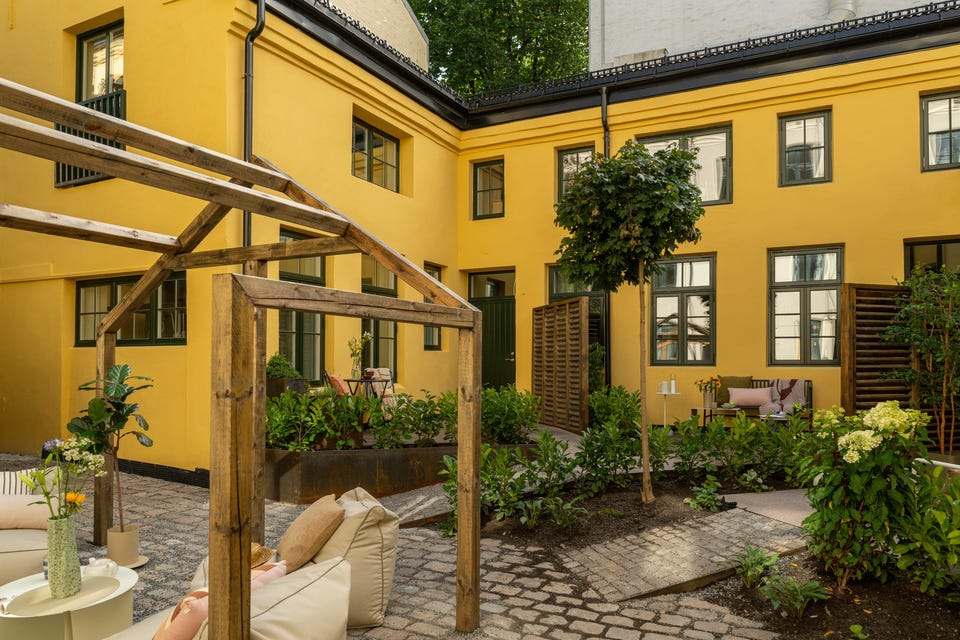 Felles pergola og sitteområde i forgrunnen. Terrassearealene langs fasaden er fordelt til enkelte boliger og er ikke felles sitteplasser.