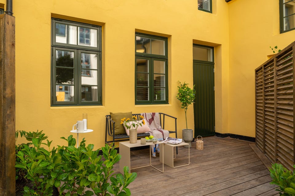 Egen inngang og terrasse ved den gule murfasaden - et nytt hjem i et skjermet, historisk bakgårdsmiljø.