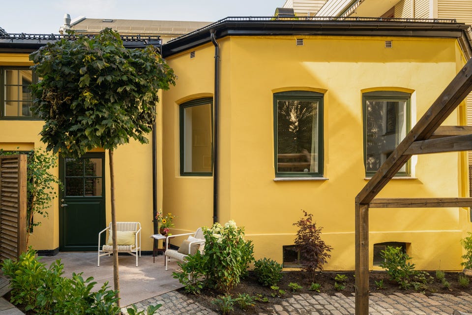 Bakgårdsbyggets gule fasade vender mot det lukkede gårdsrommet. Terrassearealene langs fasaden er fordelt til enkelte leiligheter.