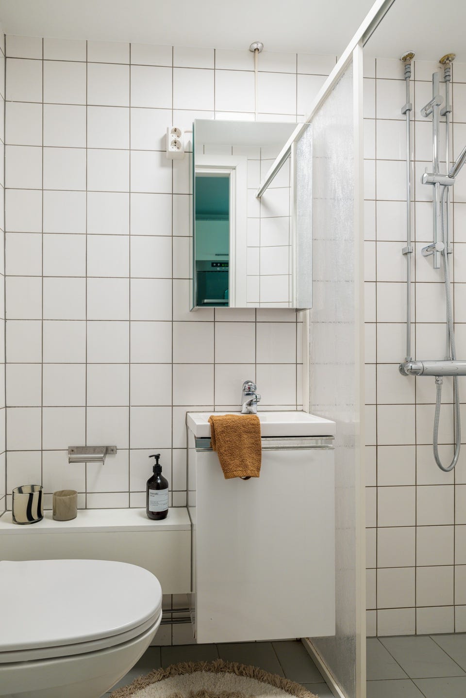 Separat, flislagt bad med dusjhjørne, servantinnredning og toalett.