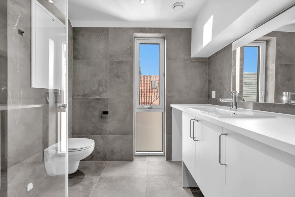 Badet er moderne med fliser på vegger og gulv.