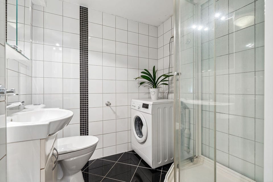 Tiled bathroom with shower cabinet, washbasin, toilet and plumbing for a washing machine.