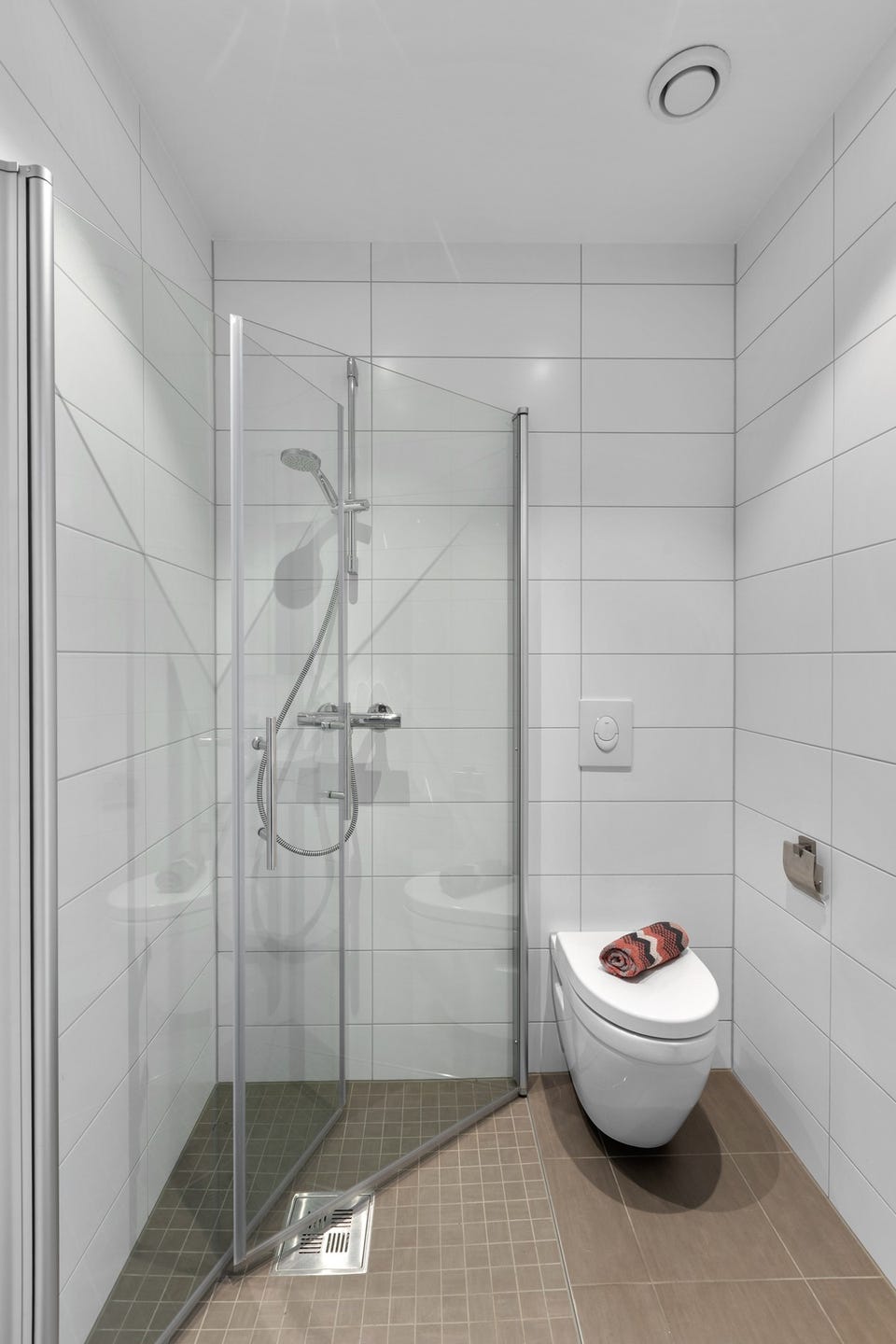 Det er videre adkomst til baderom 2. Baderommet har fliser på gulv og vegger, elektrisk gulvvarme, downlights i himlingen og avtrekk via balansert ventilasjon.