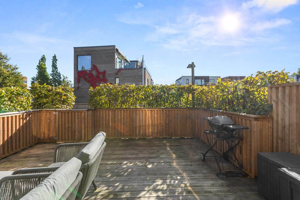 Det er utgang til en solrik sydvendt terrasse på 23m². Terrassen har terrassebord på gulv og rekkverk av tre med port ut til fellesarealene.