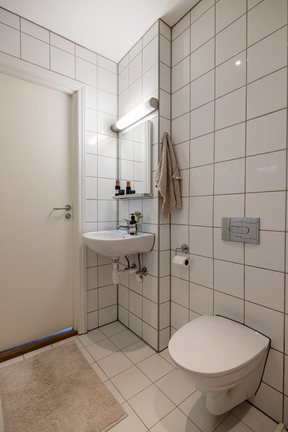 Baderommet er utstyrt med vegghengt servant med speil og belysning over, dusjhjørne med forheng, vegghengt toalett og opplegg for vaskemaskin.