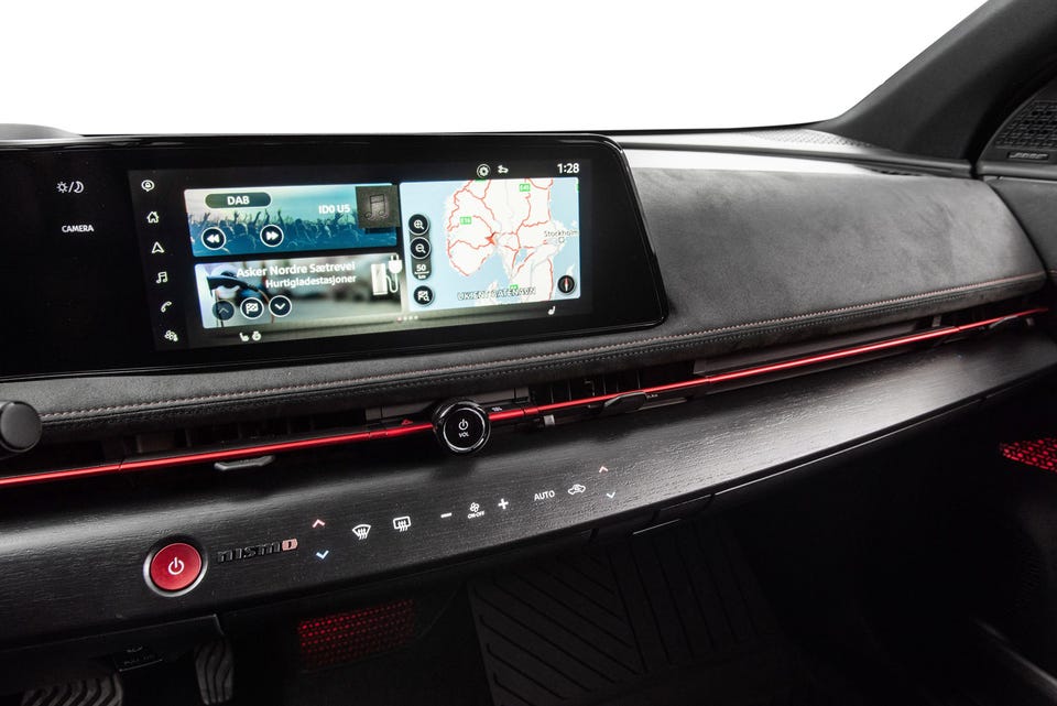 Bred infotainmentskjerm, rødt ambient lys, Nismo-detaljer og mørke alcantara-overflater