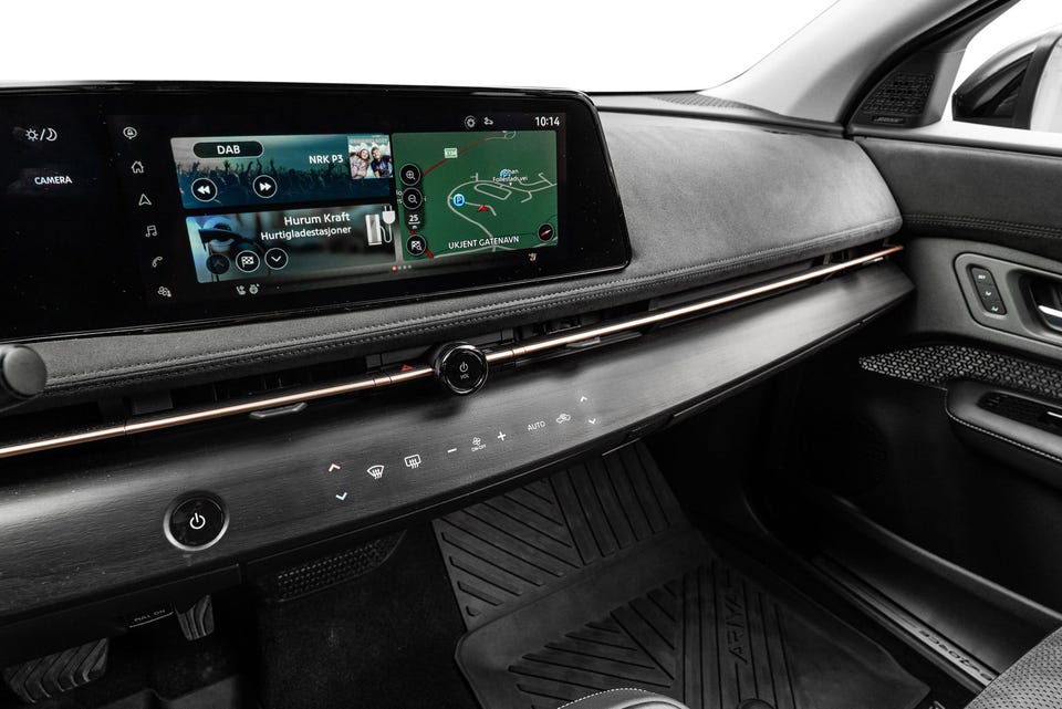 Bred infotainmentskjerm, minimalistisk dashbord med kobberfarget detalj og touch-kontroller