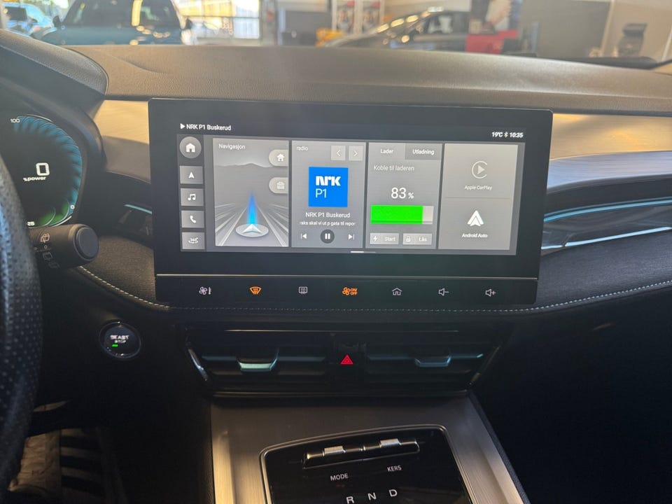 Stor infotainmentskjerm med Apple CarPlay og Android Auto, mørke interiørdetaljer og turquoise aksenter