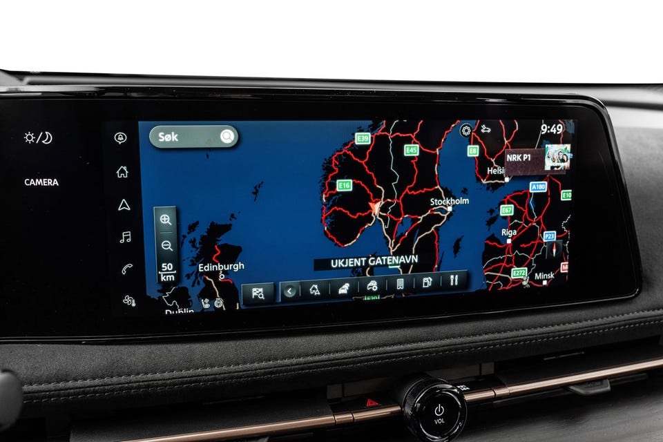 Bred infotainmentskjerm med integrert navigasjon, mørkt dashbord med bronsedetaljer og premium finish