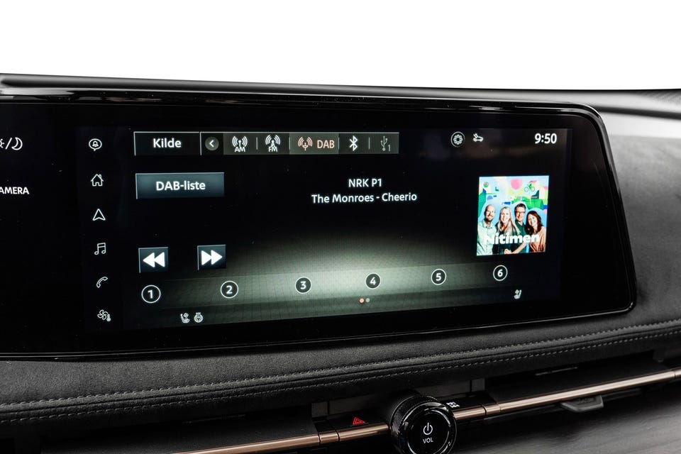 Bred infotainmentskjerm med DAB-radio, mørke materialer og bronsefarget detaljeList