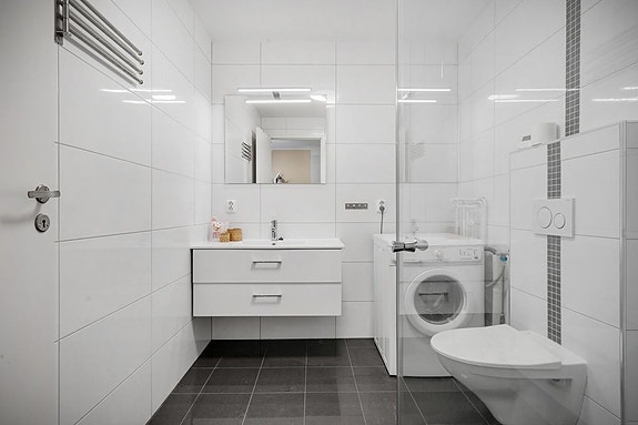Badet er innredet med dusj, toalett, servant og opplegg for vaskemaskin og tørketrommel.