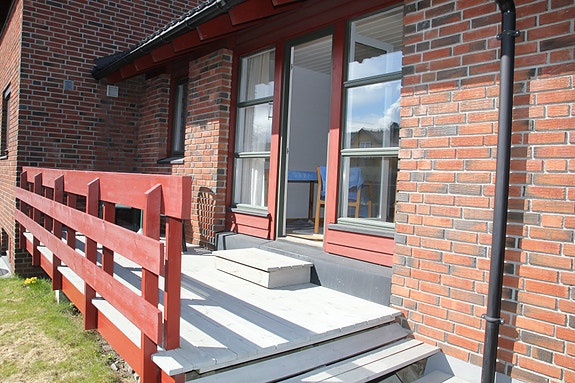 Leiligheten har en fin sørvendt veranda med en liten gressplen foran. (Du trenger ikke tenke på å klippe plenen selv.) Rikelig sollys slipper inn i stuen som er på innsiden av verandadøren.