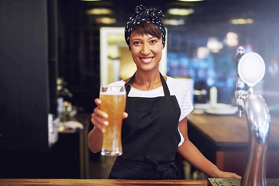 Kvinnelig bartender overrekker øl
