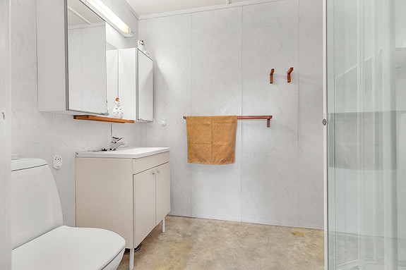 Praktisk baderom som er utstyrt med toalett, servant og skap med god plass for diverse baderomsartikler.
