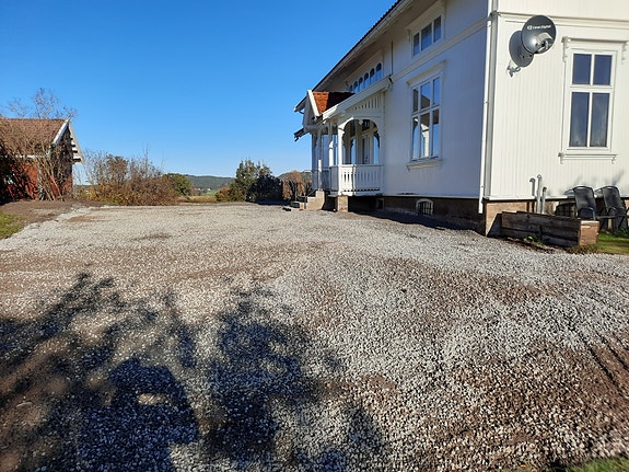 Inngangspartiet til leiligheten. Det er tak over inngangspartiet tilhørende leiligheten. To parkeringsplasser.