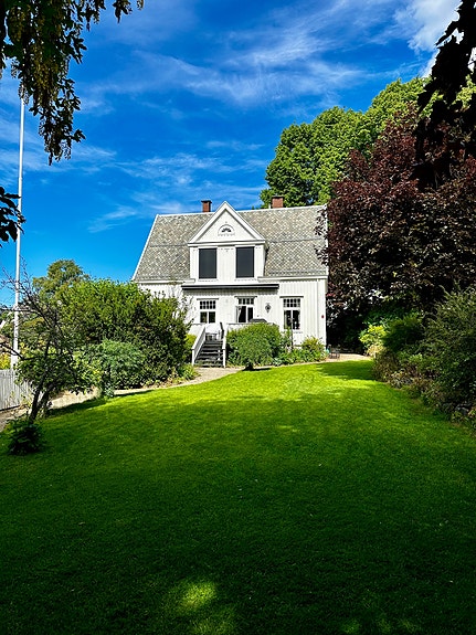 Eiendommens fasade. Leietakers tilgang er skjermet bak vegetasjon til venstre for huset.