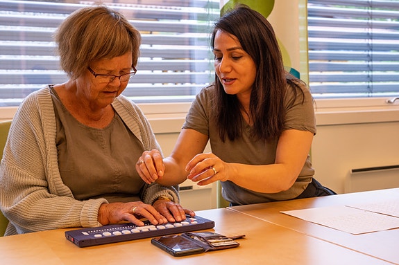 En person får opplæring i bruk av mobiltelefon og leselist