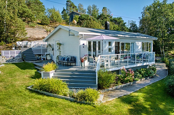 Dette er en elegant og sommerlig hytte tegnet av arkitekt Per Bjar - beliggende kun 75 meter fra sjøkanten og båtbrygge.