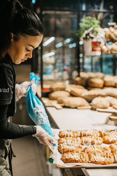 Butikkmedarbeidere assisterer baker med å tilberede bakervarer klare for disken.