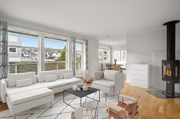 Leiligheten har en meget romslig stue med store glassflater fra gulv til tak som slipper inn rikelig med dagslys som bidrar til en behagelig romfølelse. (Møblene på bildet er manipulert inn).