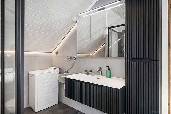 Lekkert bad fra 2024 med moderne servant i innredning og lyssatt speil.