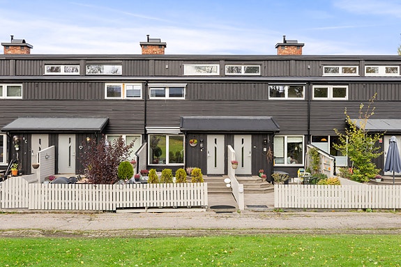 Velholdt rekkehus med moderne uttrykk og vestvendt uteplass. Tomten er pent opparbeidet med belegningsstein og beplantning.