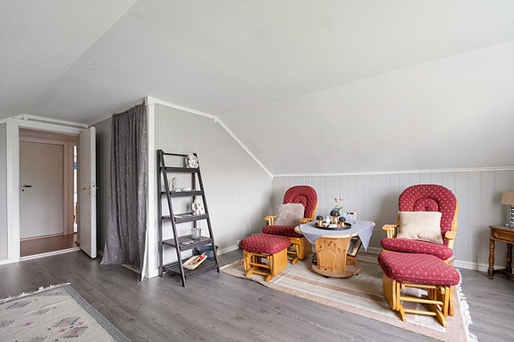 Romslig loftstue med store vinduer som slipper inn mye naturlig lys og gir utsikt mot nærområdet